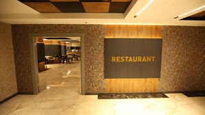 A modern restaurant interior with a marble floor, a wooden accent wall, and a sign that reads "RESTAURANT". - Büpa delüxe hotel (Kayseri)