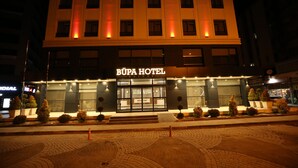 A hotel with a reception area, a sign reading "BUPA HOTEL DELUXE," and a paved entrance area with potted plants. - Büpa delüxe hotel (Kayseri)