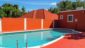 A swimming pool with a red tiled roof and a red wall, surrounded by a red surface. - Paradise On The Rocks Hotel (Negril)