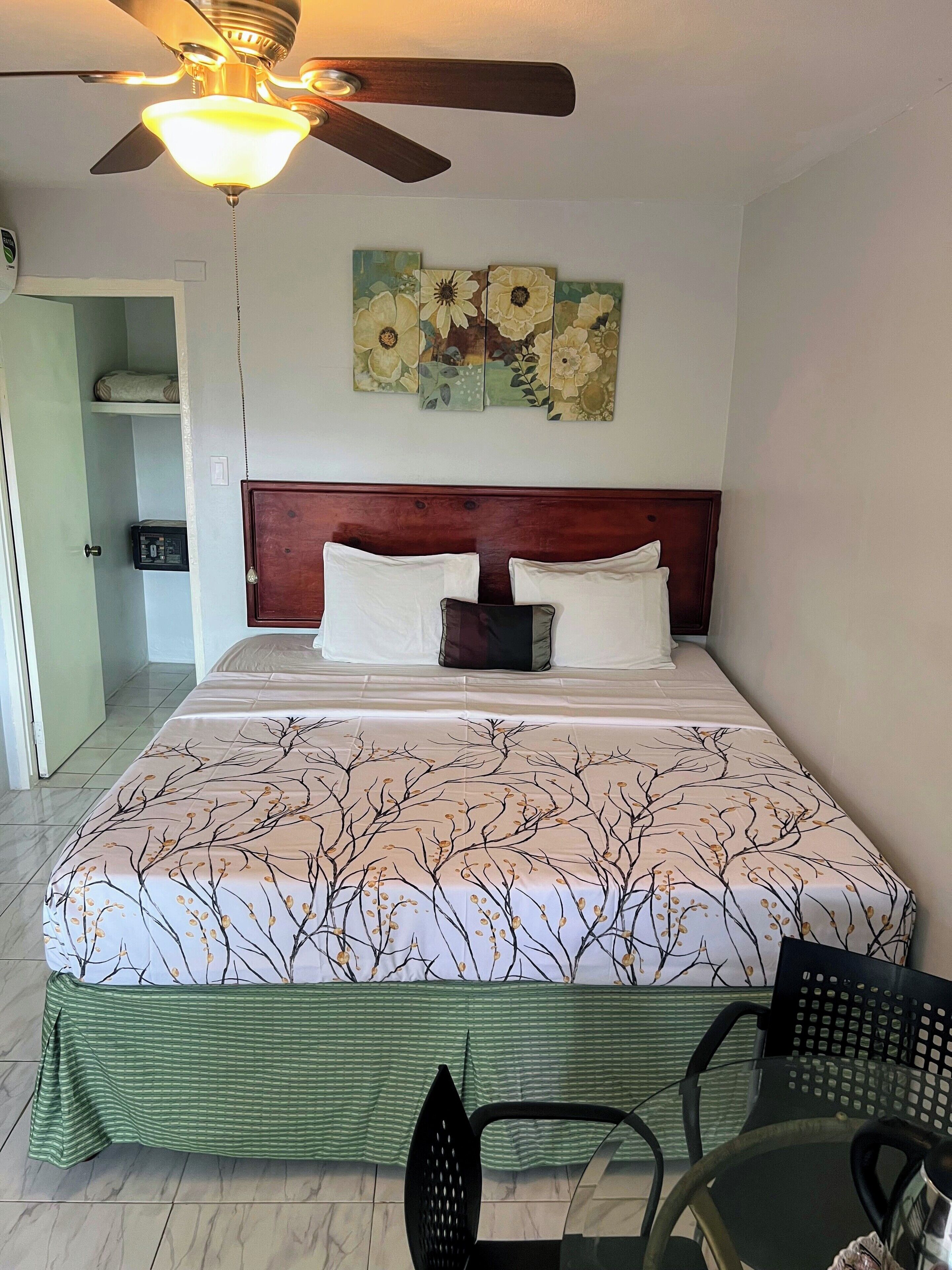 A neatly made bed with a floral bedspread, a wooden headboard, and a ceiling fan.