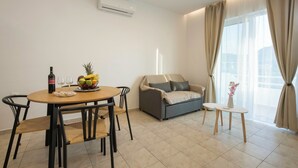 A modern living room with a dining table, sofa, and a small side table. - Kathys Apartment 1 in Archaggelos (Archangelos)