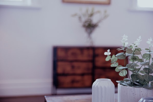 A room with a wooden cabinet, a white vase, and a potted plant with green leaves. - Holmfirth converted bank: centre of Town (Holmfirth)