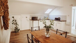 Une cuisine moderne avec des meubles blancs, une table à manger en bois et une lucarne.