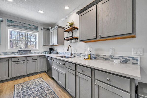 A modern kitchen with grey cabinets, a white countertop, and a window with a view of trees. - ⭐Private Pool-4 Bikes-30A-Beach Access-Claddagh Cottage⭐ (Santa Rosa Beach)