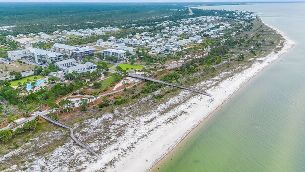 Eine Vogelperspektive eines Wohngebiets an der Küste mit Häusern, einem Strand und einer Brücke.