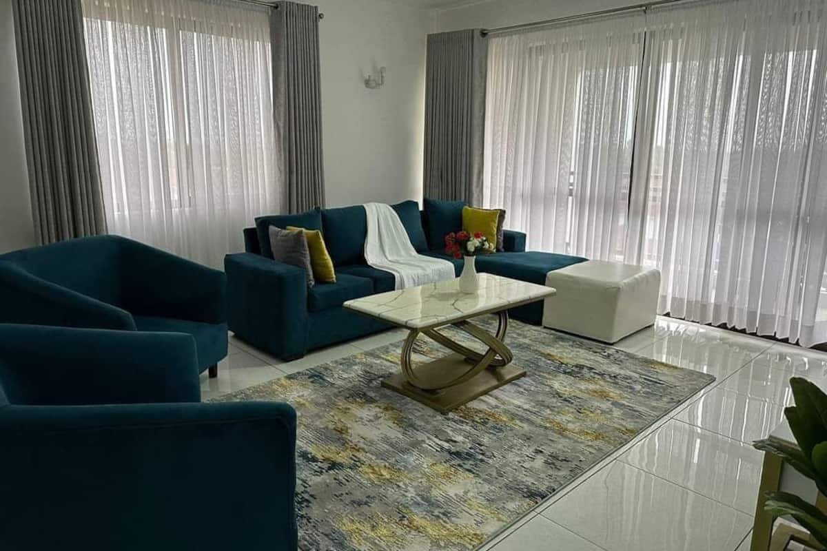 A modern living room with a blue sofa set, a white coffee table, and a patterned rug.