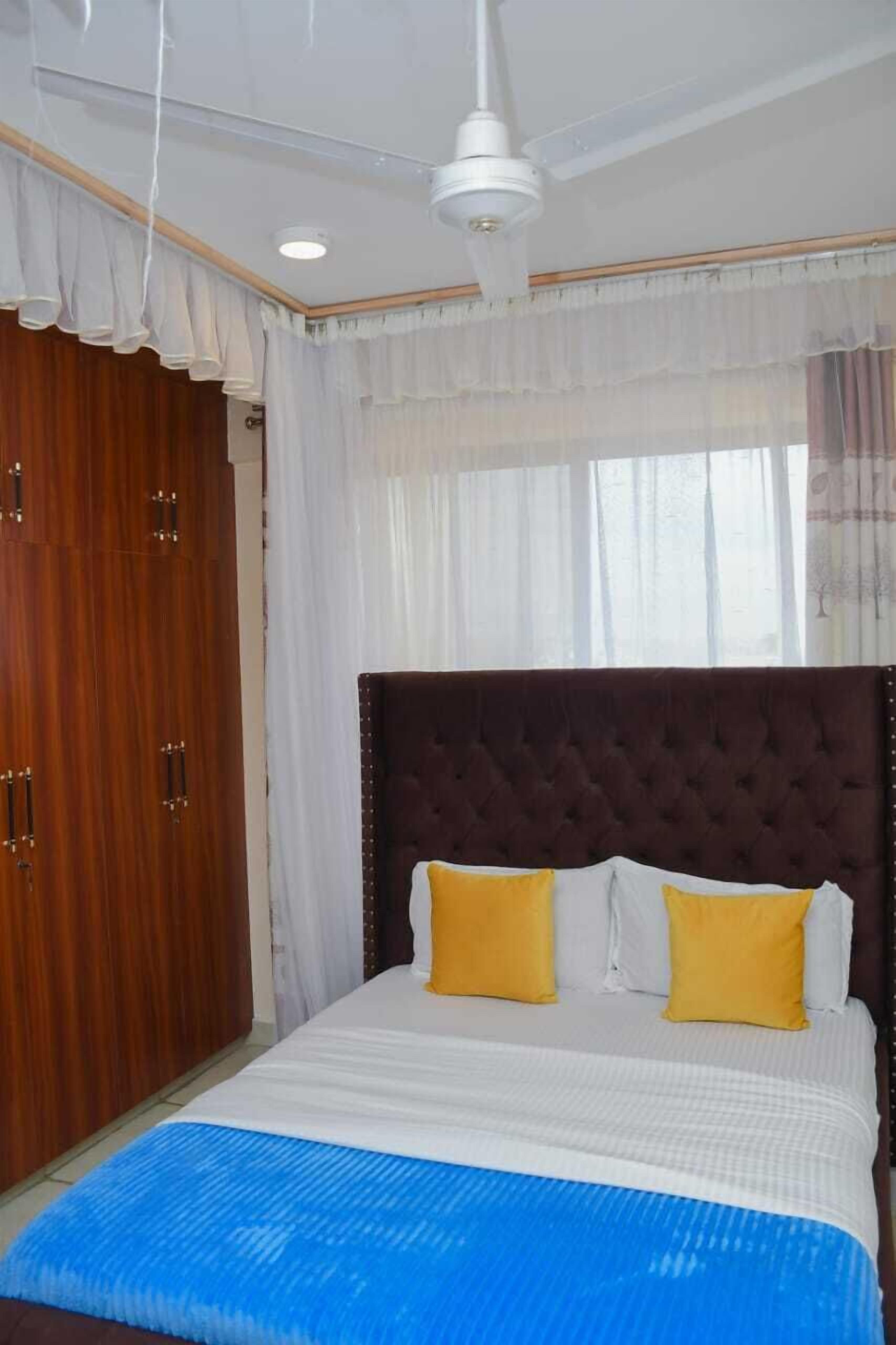 Un dormitorio con una cama grande, un ventilador de techo y un armario de madera.