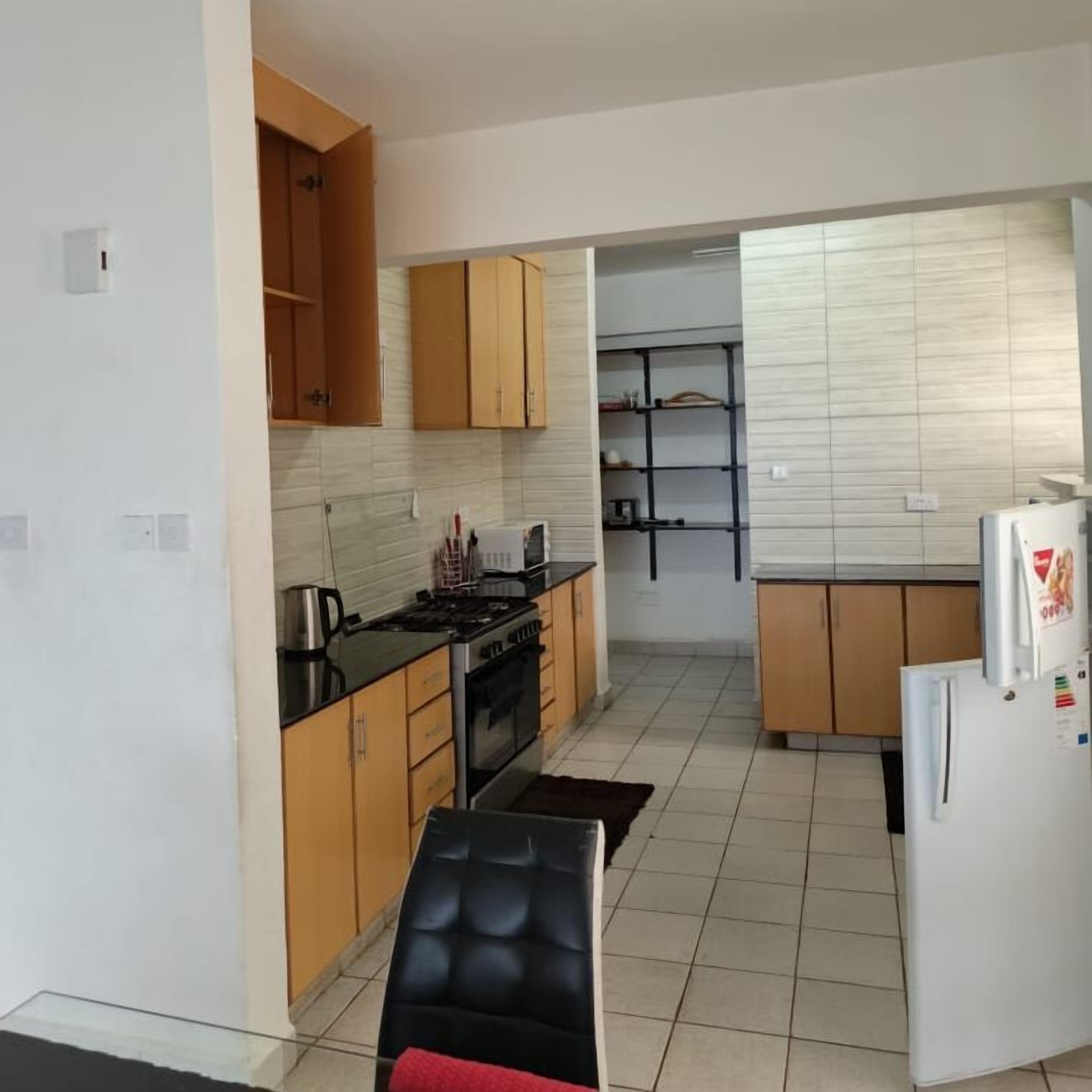 Una cocina compacta con armarios de madera, una estufa y un refrigerador.