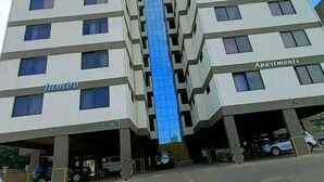 Un moderno edificio de apartamentos con un elevador central de vidrio, varios pisos y un garaje en la base.