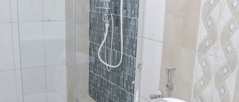 A bathroom with a shower enclosure, a toilet, and a bidet.