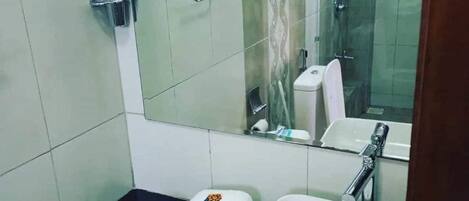 A bathroom with a white sink, a mirror, and a toilet. There is a towel and a bottle of hand soap on the counter.