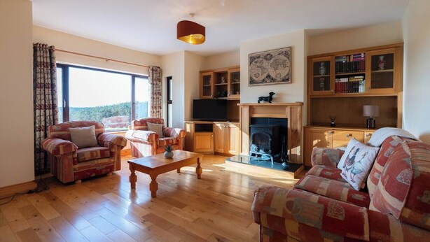 A spacious living room with a fireplace, wooden furniture, and a bookshelf.