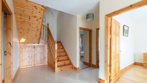 A spacious room with a wooden staircase, a large wardrobe, and a door leading to another room.