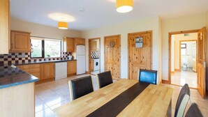 A modern kitchen with wooden cabinets, a dining table with chairs, and a view of the outside.