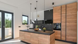 Une cuisine moderne dotée d’un grand îlot central, de meubles en bois et d’un plan de travail noir.