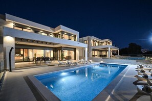 Ein modernes Hotel mit Schwimmbad, Außenbereich und einer gut beleuchteten Fassade.