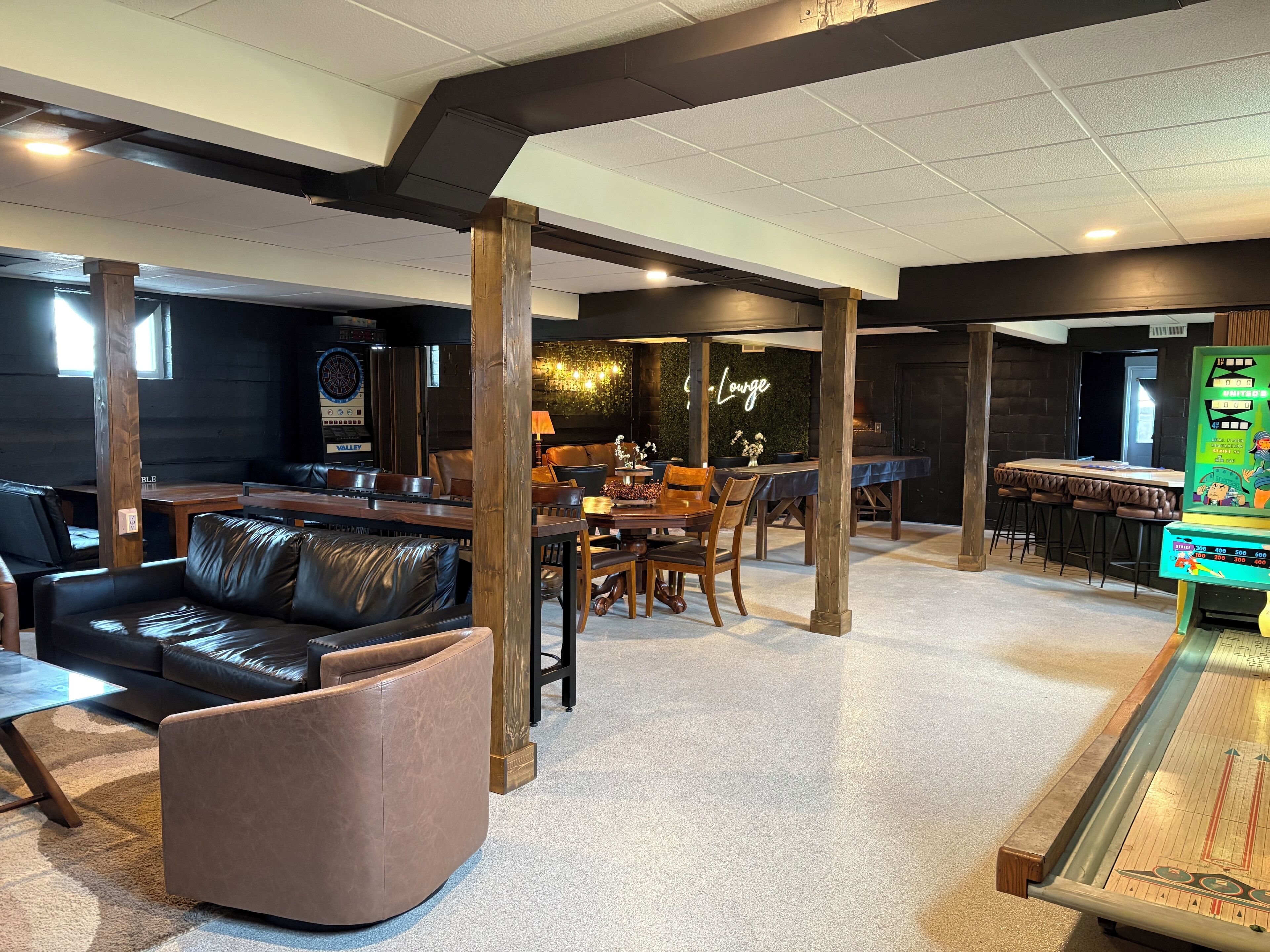 A modern lounge area with leather seating, a dining table, and a shuffleboard table.