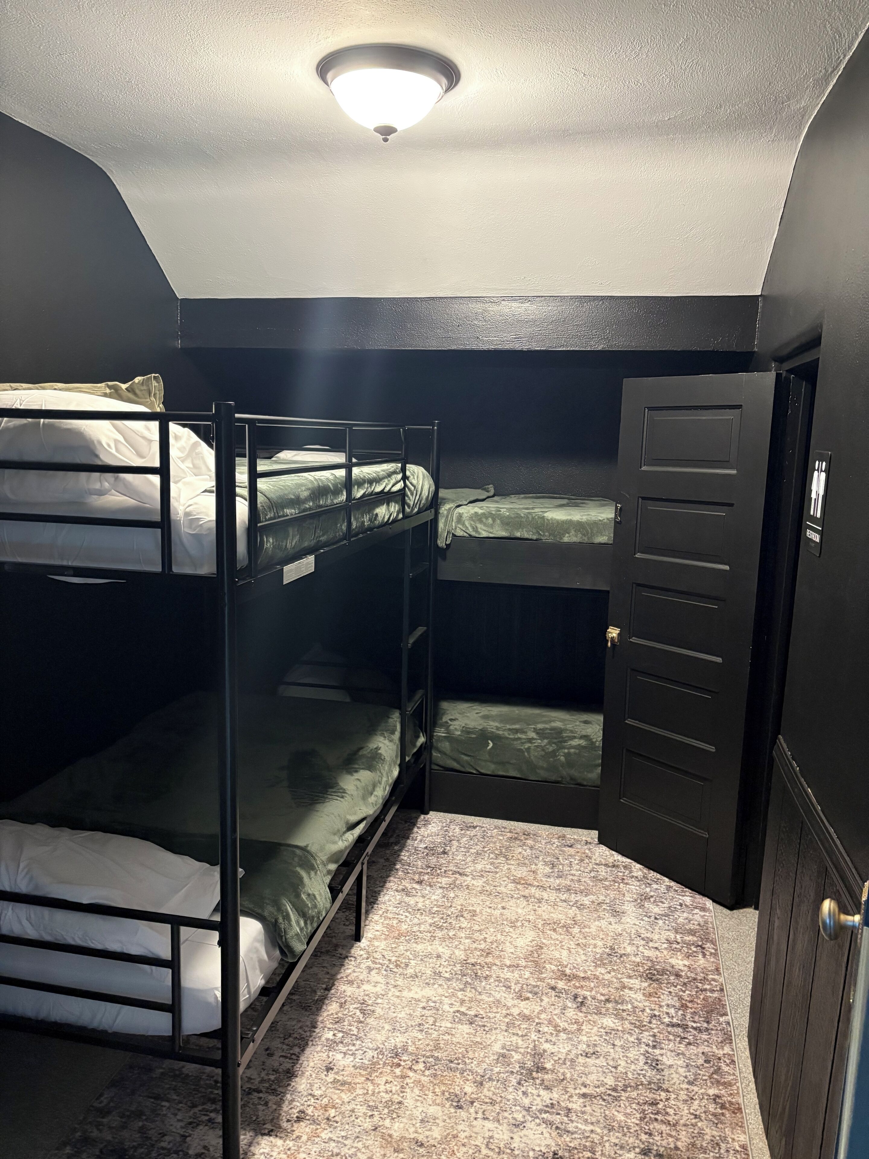 Een kamer met stapelbedden, een deur en een plafondlamp.