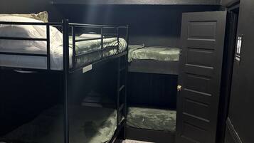 Een kamer met stapelbedden, een deur en een plafondlamp.