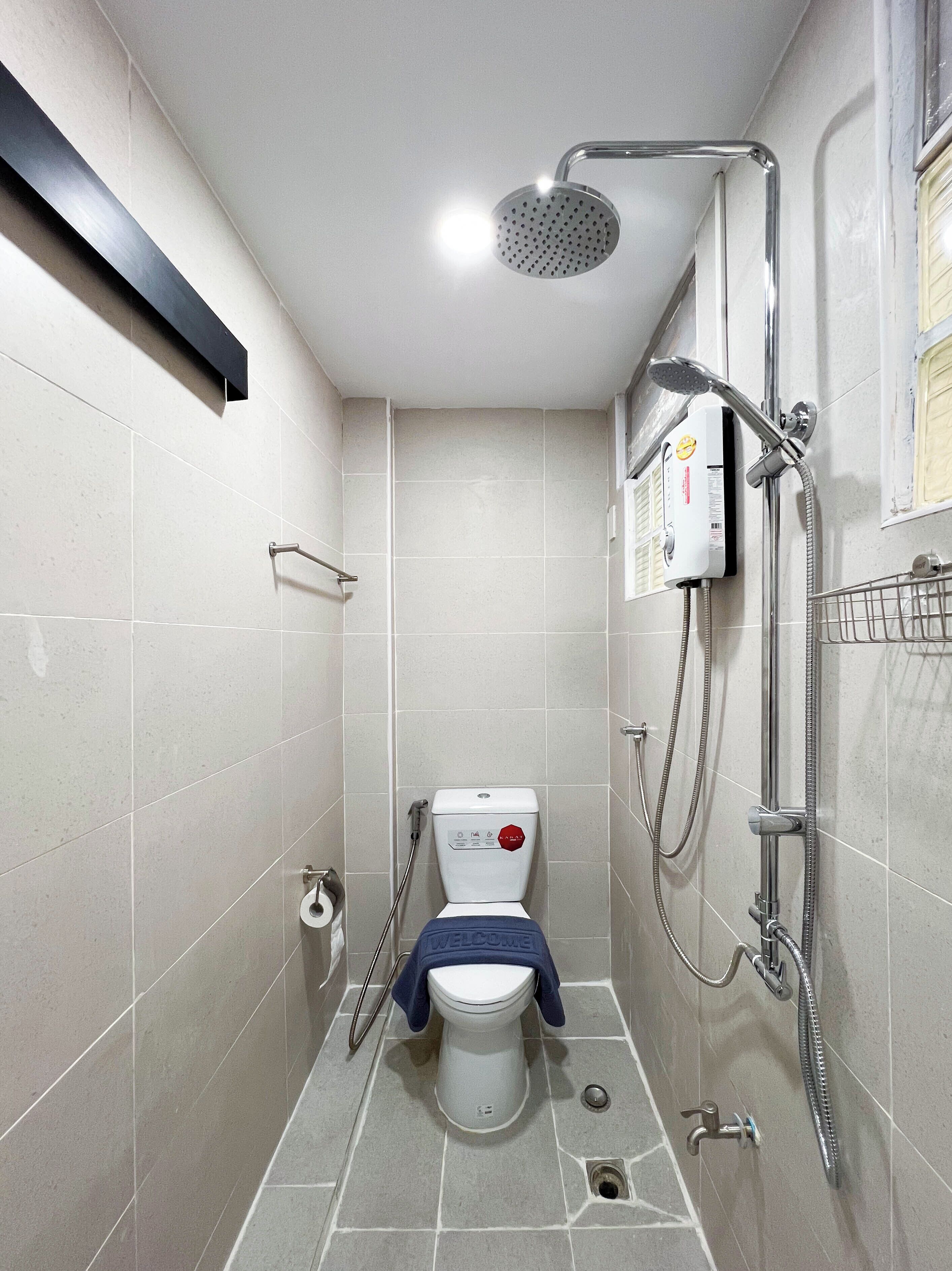 Ein kleines Badezimmer mit Toilette, Duschkabine und Handtuchhalter.