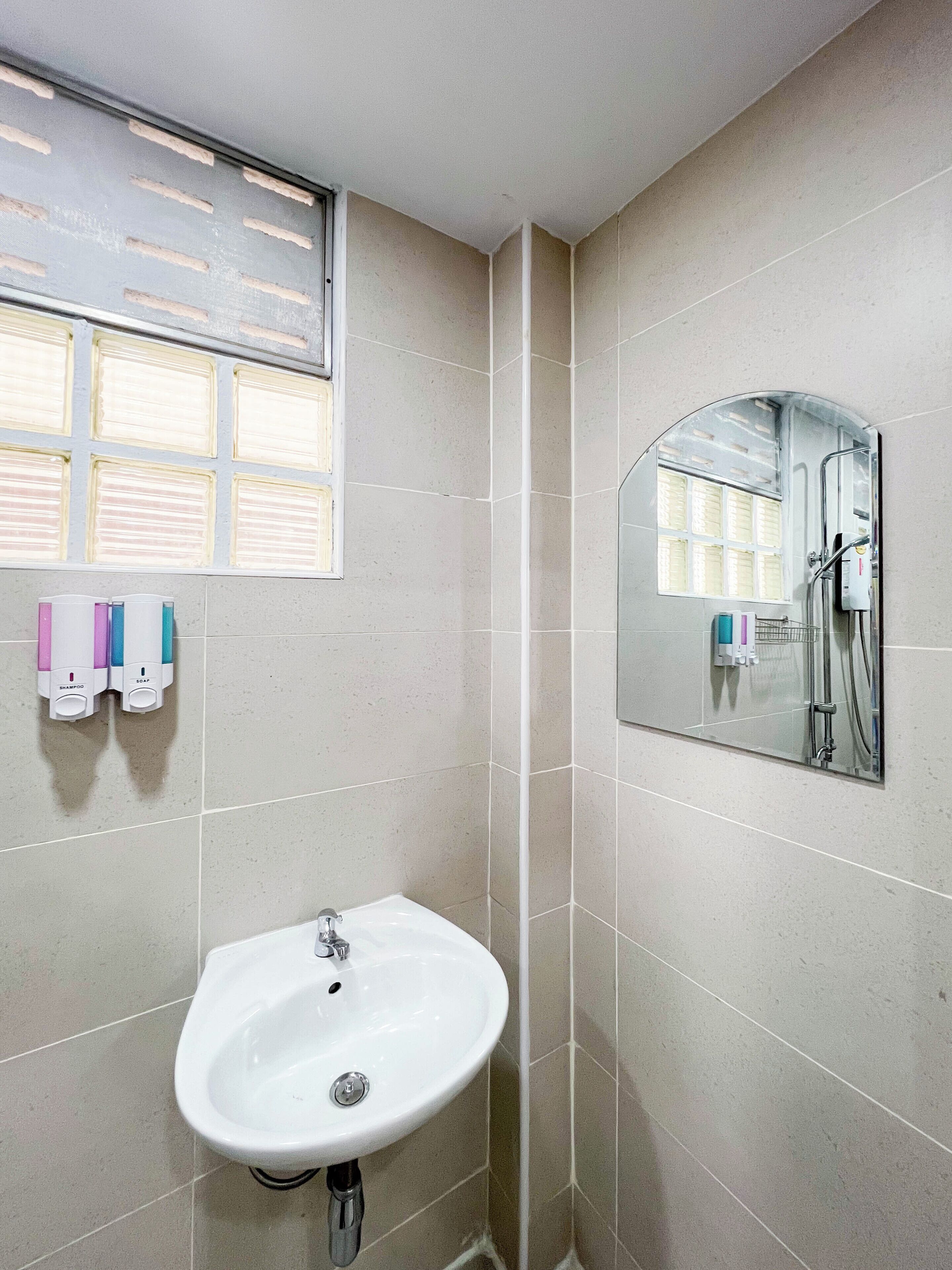 Une salle de bain avec un lavabo, un miroir et une fenêtre avec des stores.