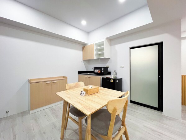 A compact kitchen with a dining table and chairs, a microwave, and a refrigerator. - C You Home at CNX (Chiang Mai)