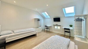 Un dormitorio moderno y luminoso con cama en altillo, escritorio y televisor.
