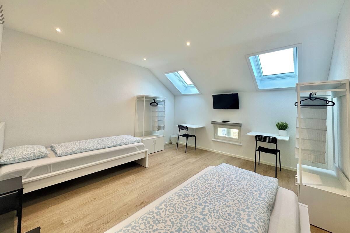 A modern, well-lit bedroom with a loft bed, a desk, and a TV.