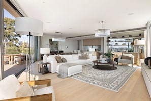A spacious living area with a large sofa, a coffee table, and a dining area with a table and chairs. - Luxury Villas Como Penthouse (Melbourne skyline and river views) (South Yarra)