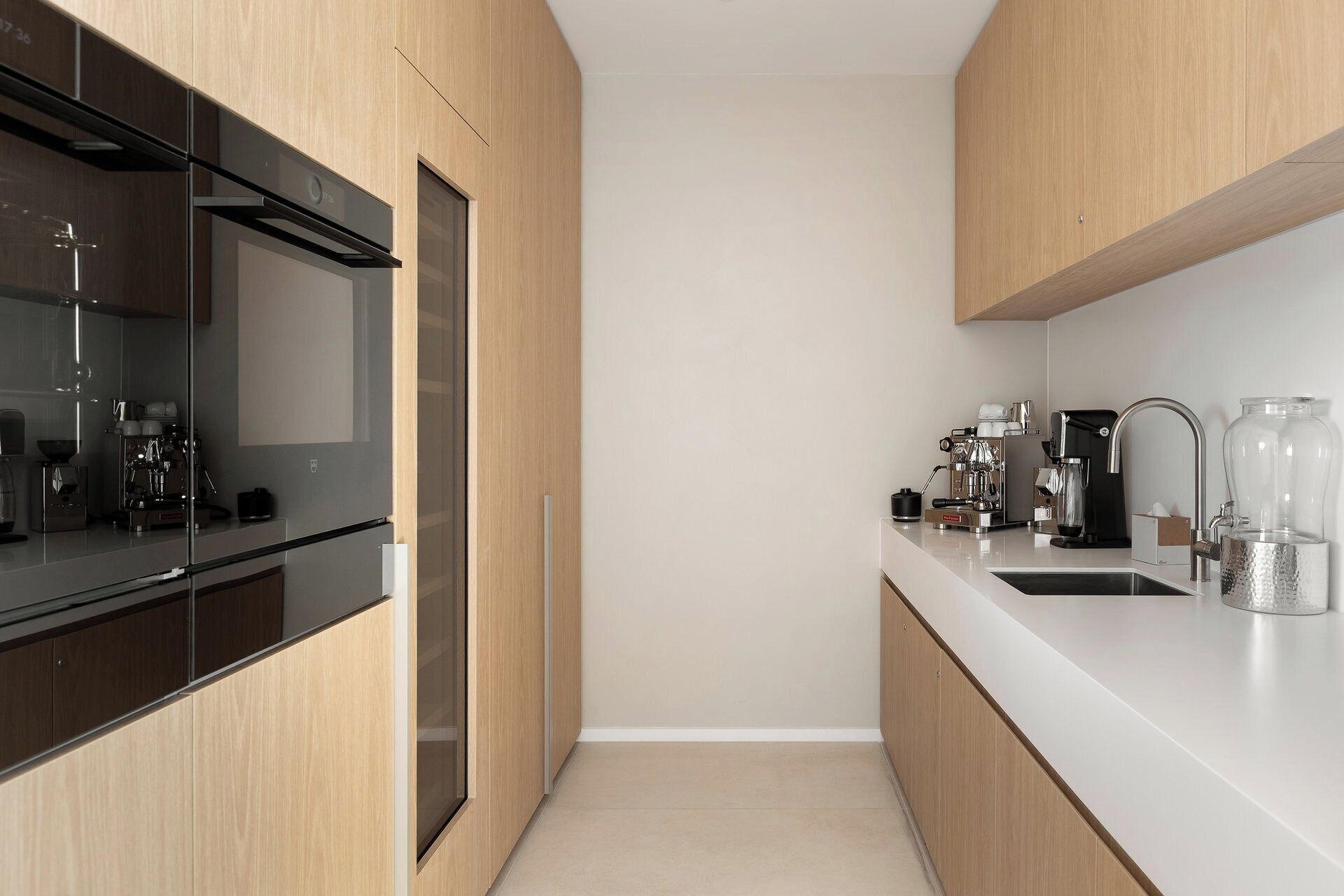 A modern kitchen with a built-in oven, a coffee machine, and a sink.
