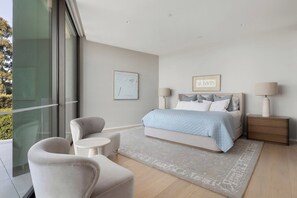 A modern bedroom with a large bed, bedside tables, a chair, and a rug. - Luxury Villas Como Penthouse (Melbourne skyline and river views) (South Yarra)