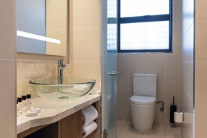A modern bathroom with a glass bowl sink, a toilet, and a window providing natural light. - Mpilo Boutique Hotel (Maseru)
