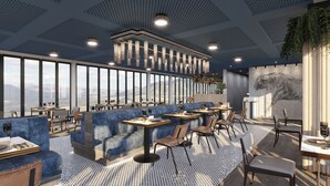 Ein modernes Restaurant mit hohen Decken, großen Fenstern und Bergblick.