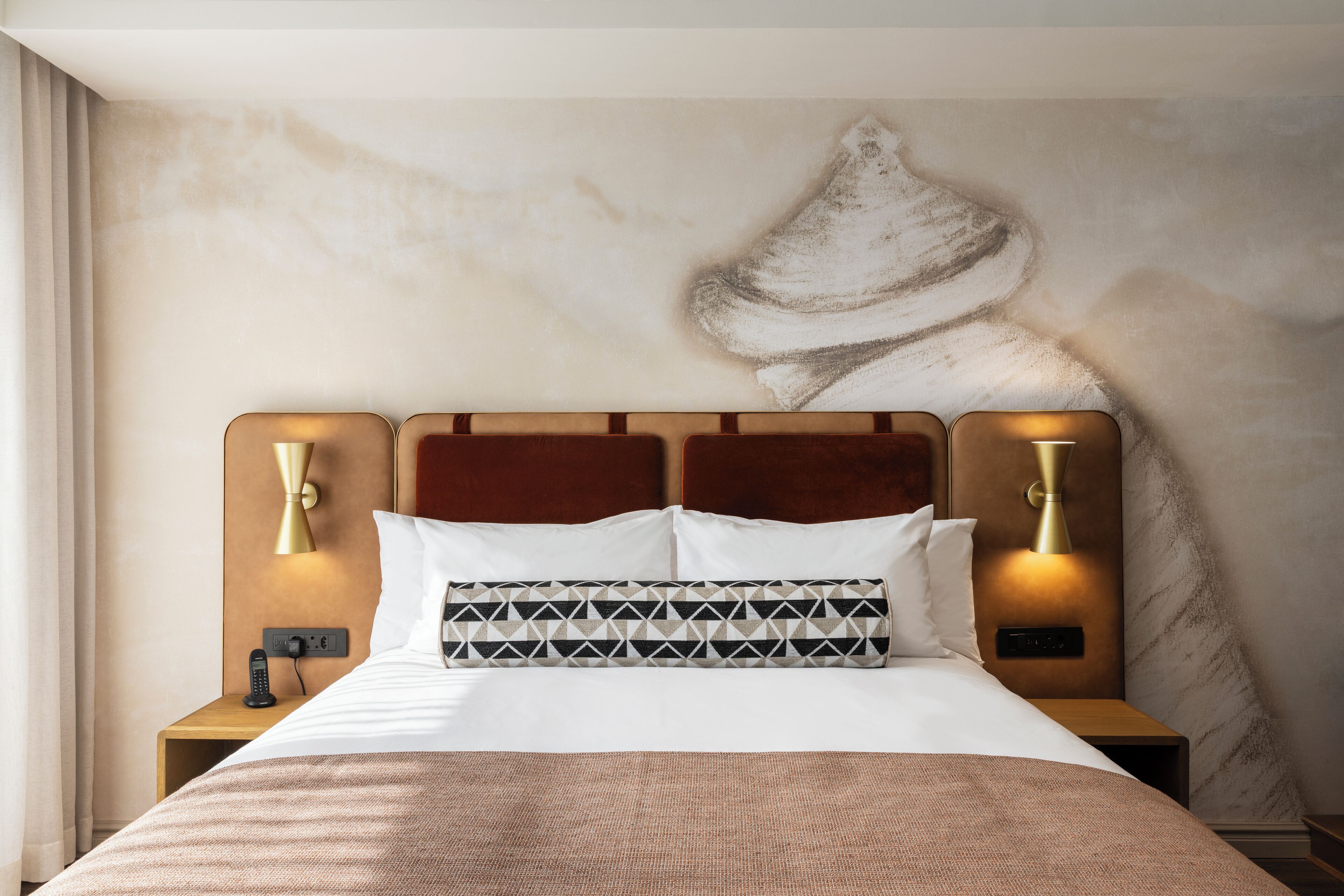 A hotel room with a large bed, two bedside tables, a wall-mounted light fixture, and a textured wall design.