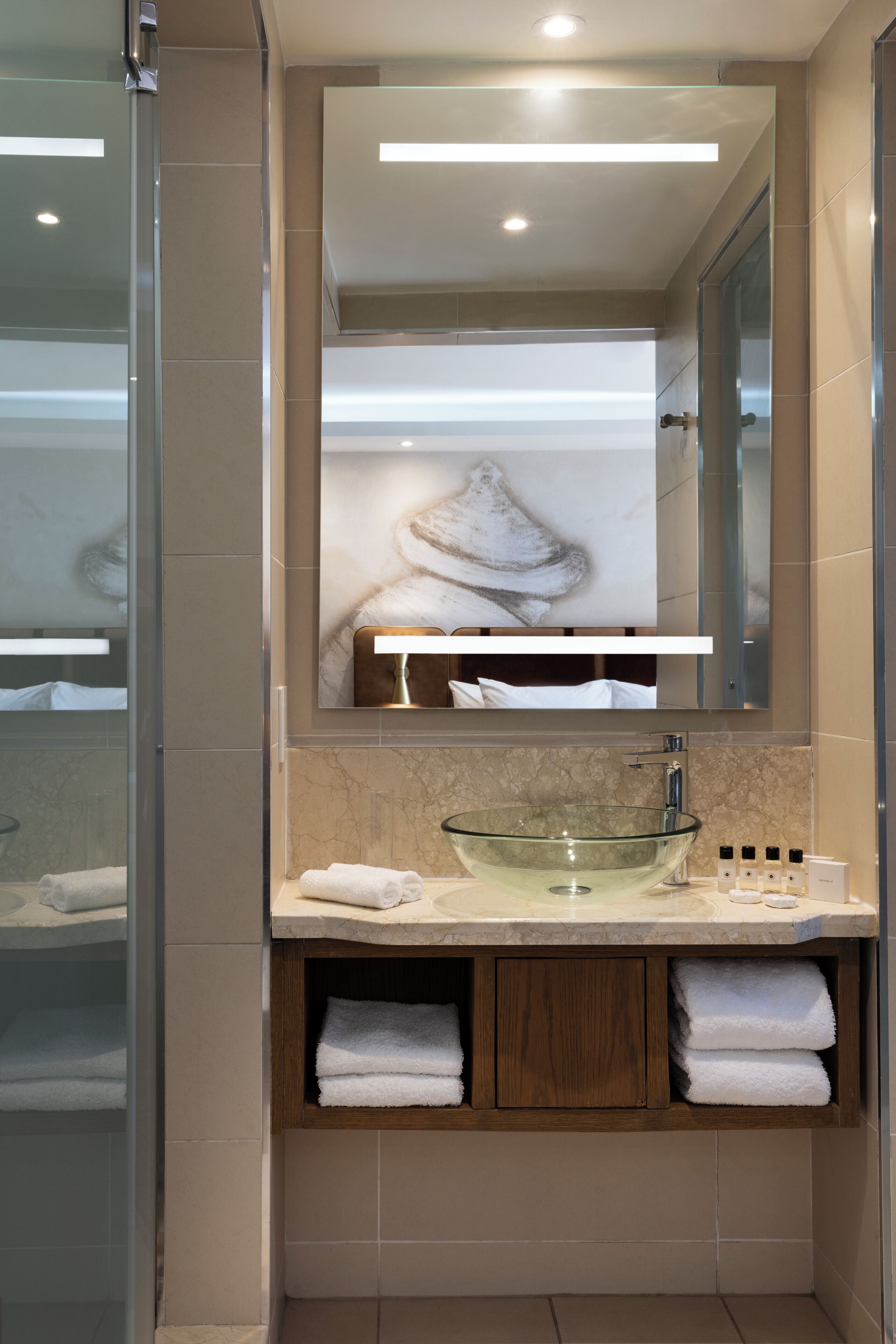 A modern bathroom with a glass bowl sink, a large mirror, and a wooden cabinet below.