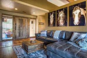 A living room with a leather sofa, a wooden coffee table, and three horse paintings on the wall.
