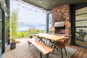 An outdoor dining area with a brick fireplace, wooden table, and benches. - Luxury Mansion in Dublin 18 (Kilgobbin)