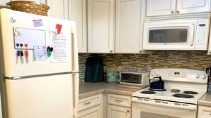 Eine Küche mit weißen Schränken, einem Kühlschrank, einer Mikrowelle, einem Backofen und einem Toaster.
