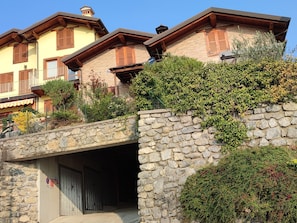 A stone bridge leading to a building with multiple balconies and wooden shutters. - Oasi Azzurra - Three-room apartment in a small villa with a terrace and a view of Lake Iseo (Fonteno)