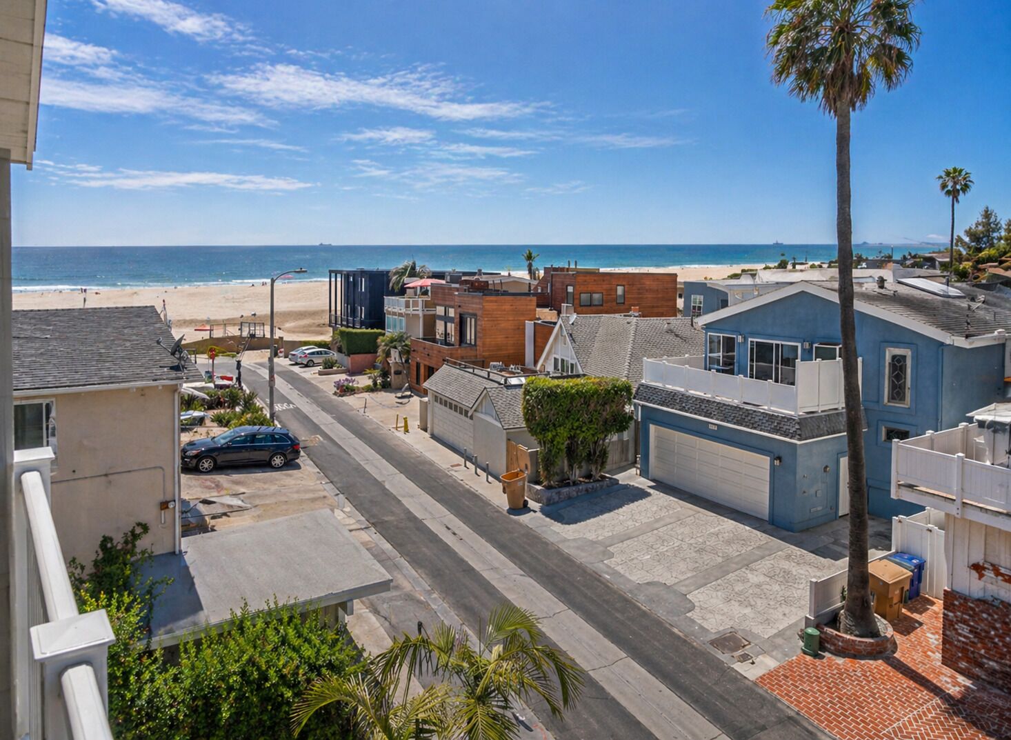Un quartier résidentiel situé sur la côte, avec une rue, des maisons et une plage en arrière-plan.