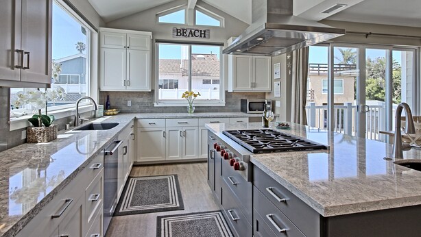 A modern kitchen with white cabinets, a large island with a stove, and a view of the outside. - Perfect 4 Families, Walk To Beach, Amazing Views* (Ventura)