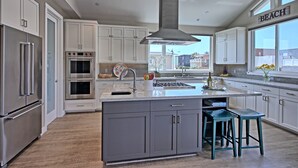 A modern kitchen with white cabinets, stainless steel appliances, and a large island with bar stools. - Perfect 4 Families, Walk To Beach, Amazing Views* (Ventura)