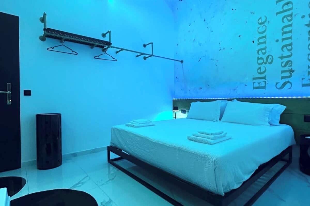 A modern bedroom with a bed, a wall-mounted rack, and a text wall.