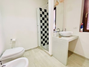 A bathroom with a toilet, a sink, and a shower with a checkered glass door.