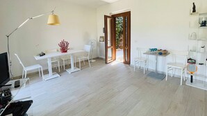 A spacious room with a large dining table and chairs, a standing lamp, and a small table with items on it. - Charming Porto Santo Stefano Apartment With Pool Access (Monte Argentario)