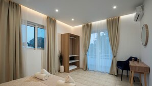 A hotel room with a bed, a desk, a wardrobe, and a view of the outside. - Kathys Apartment 2 in Archaggelos (Αρχαγγελος)