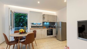 A modern kitchen with a dining area, a large window, and a view of trees. - Kathys Apartment 2 in Archaggelos (Αρχαγγελος)