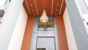 A modern building with a wooden ceiling, a large chandelier, and a glass window. - The Crown Leela (Pratapgarh)