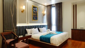 A modern hotel room with a large bed, wooden floor, a desk, and a chair. - The Crown Leela (Pratapgarh)