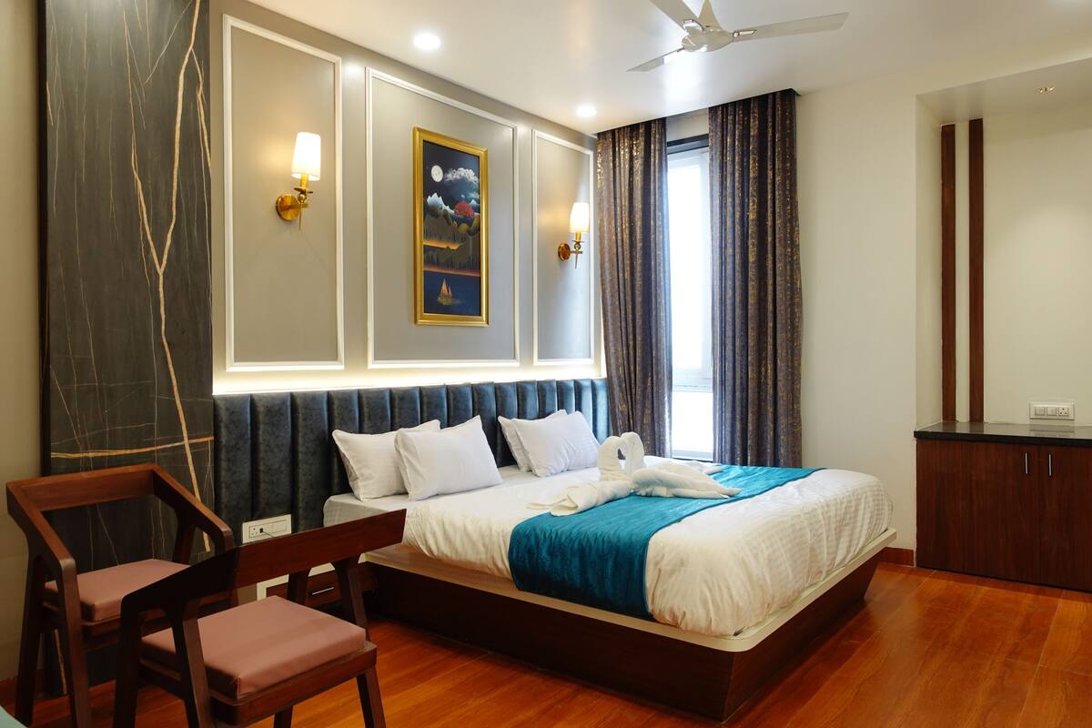 Une chambre d’hôtel moderne avec un grand lit, un plancher en bois, un bureau et une chaise.